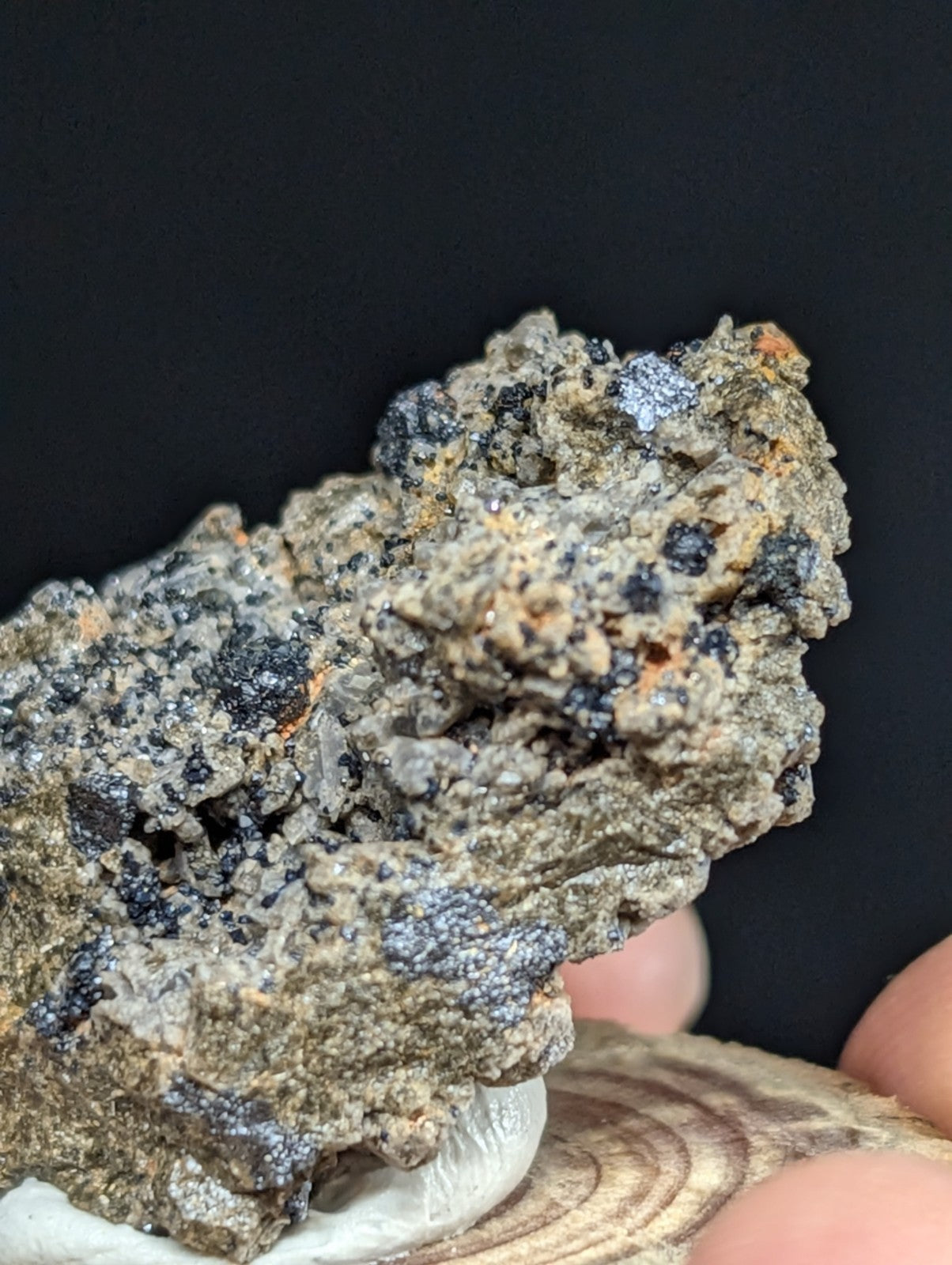A rugged, grayish mineral specimen with dark black and speckled blue crystalline formations.
