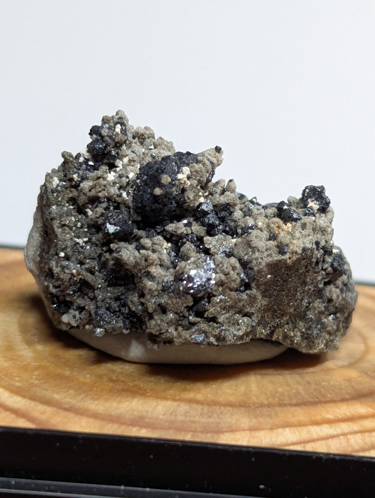 A rugged, irregularly shaped mineral specimen with a textured surface of grayish-green and black crystalline formations.