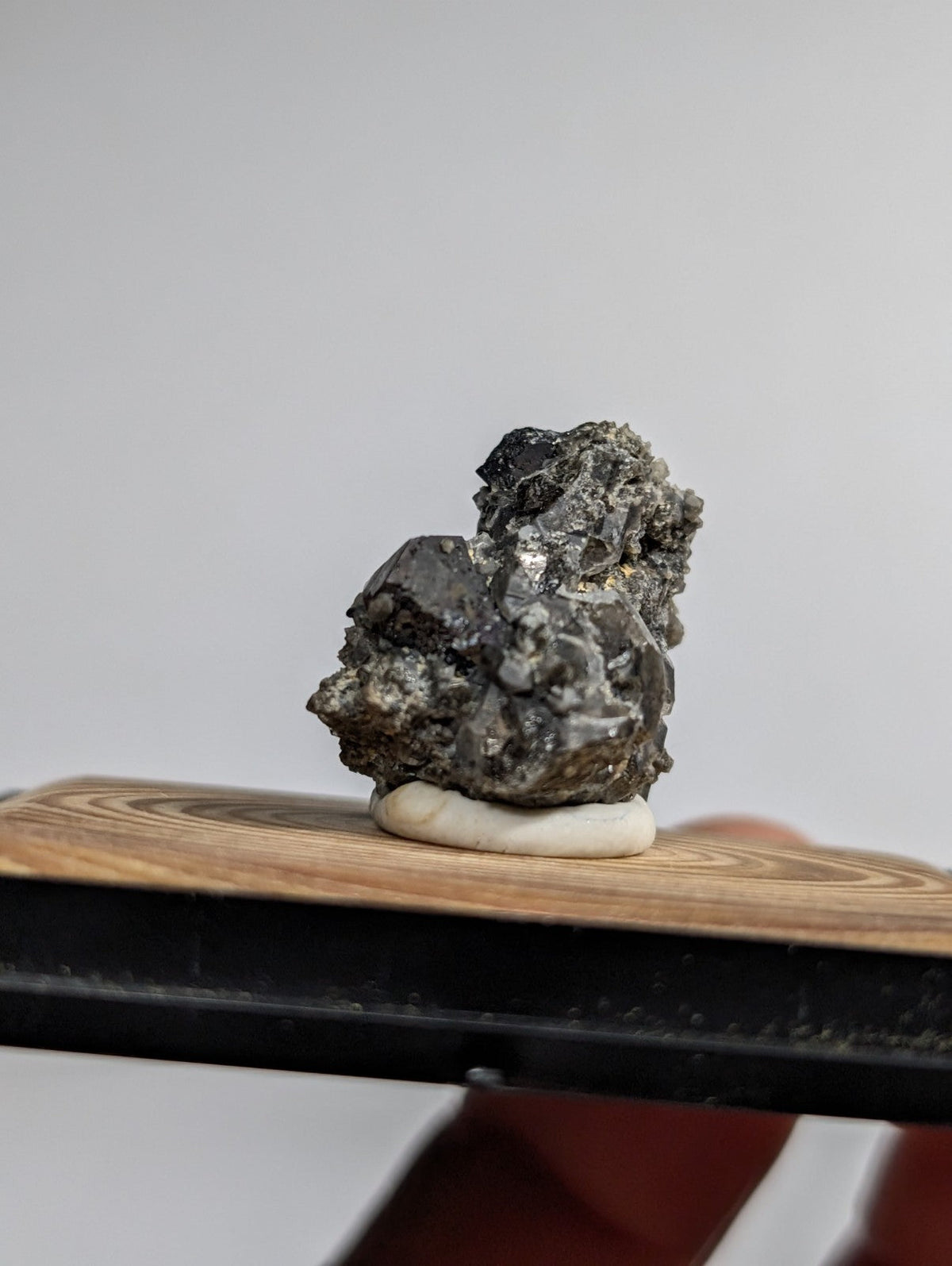 A dark, textured mineral specimen with metallic sheen and rough crystalline formations.