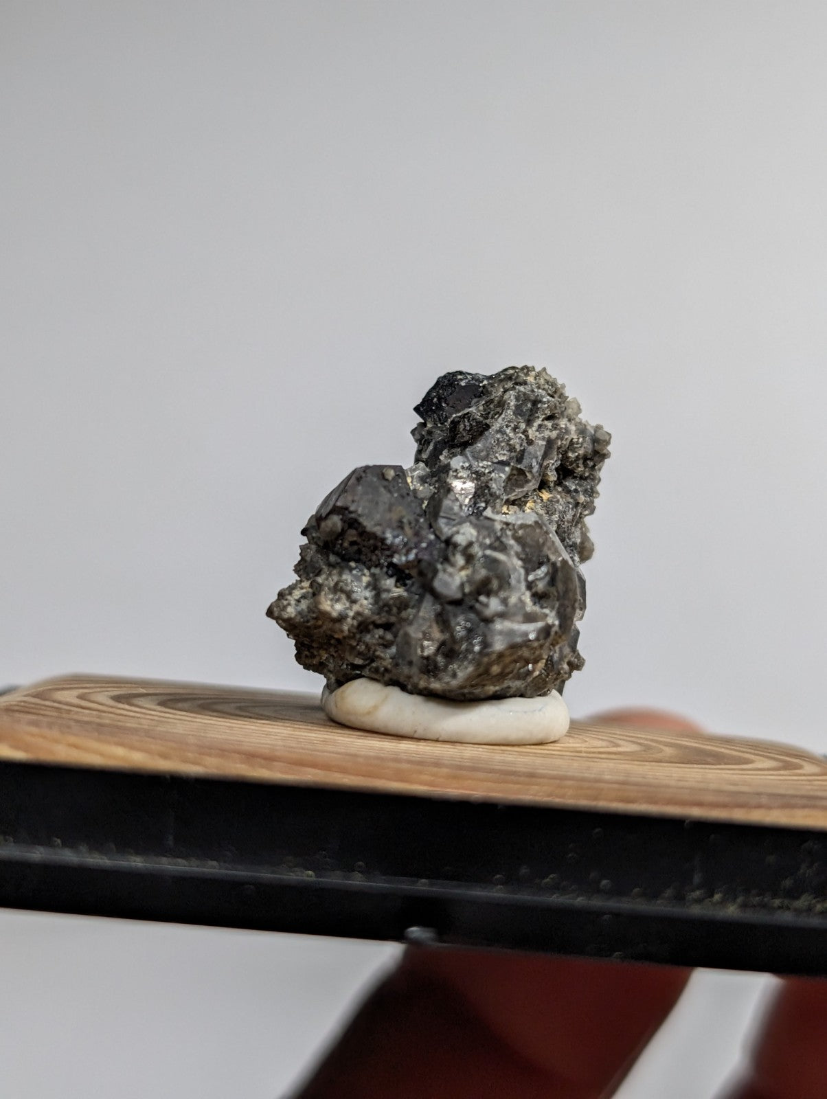 A dark, textured mineral specimen with metallic sheen and rough crystalline formations.