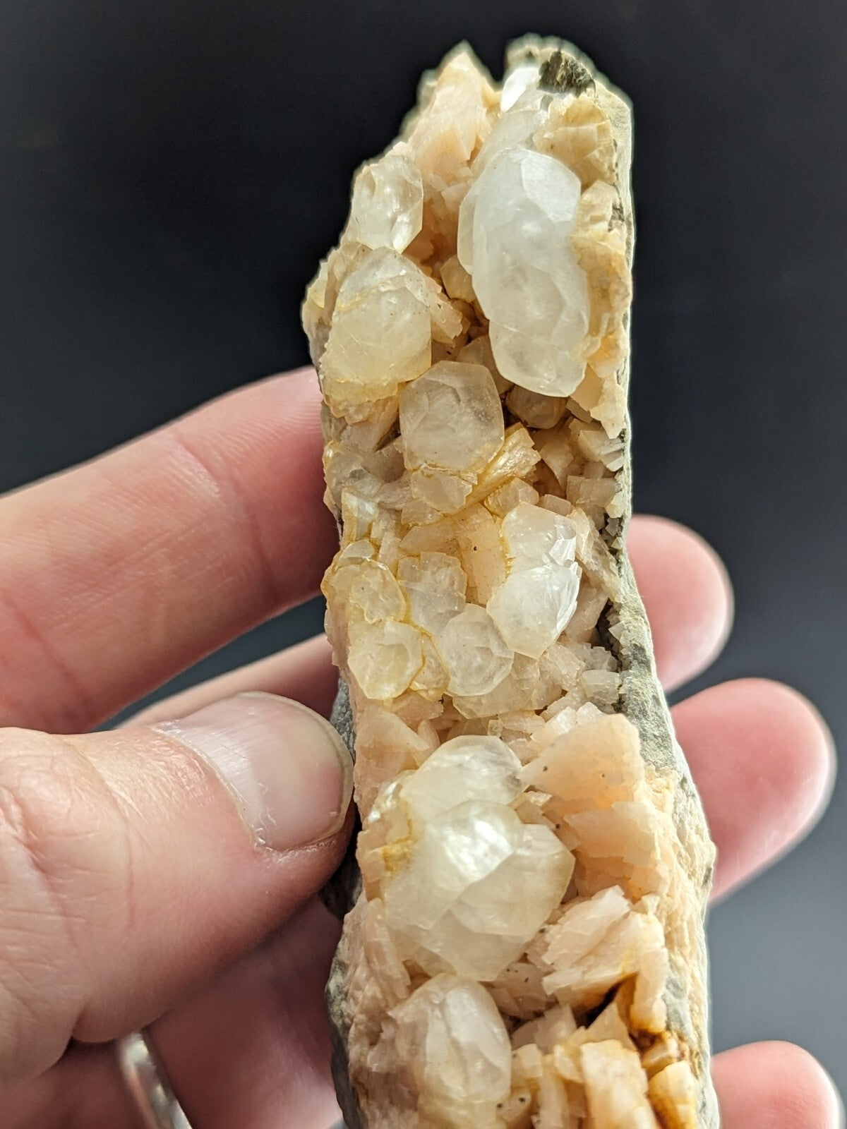 A translucent, pale yellow and white quartz crystal cluster embedded in a dark matrix.