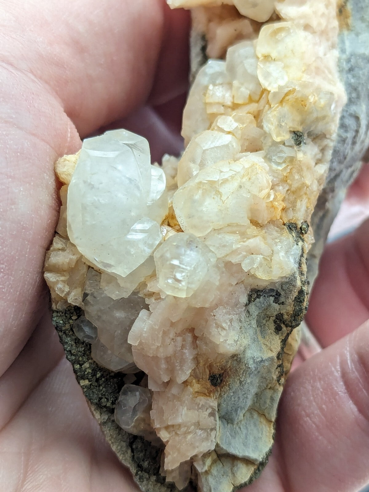 A cluster of translucent, pale yellow and white crystals growing from a rough, grayish rock matrix.