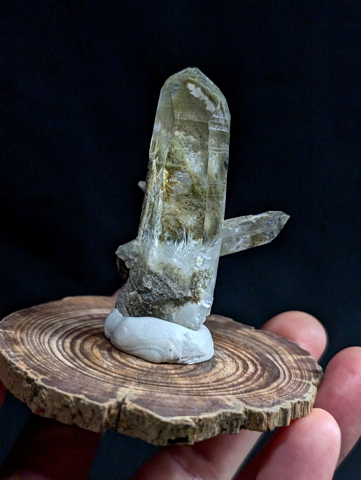 A translucent green and white quartz crystal cluster with natural striations, mounted on a rustic wooden slice.