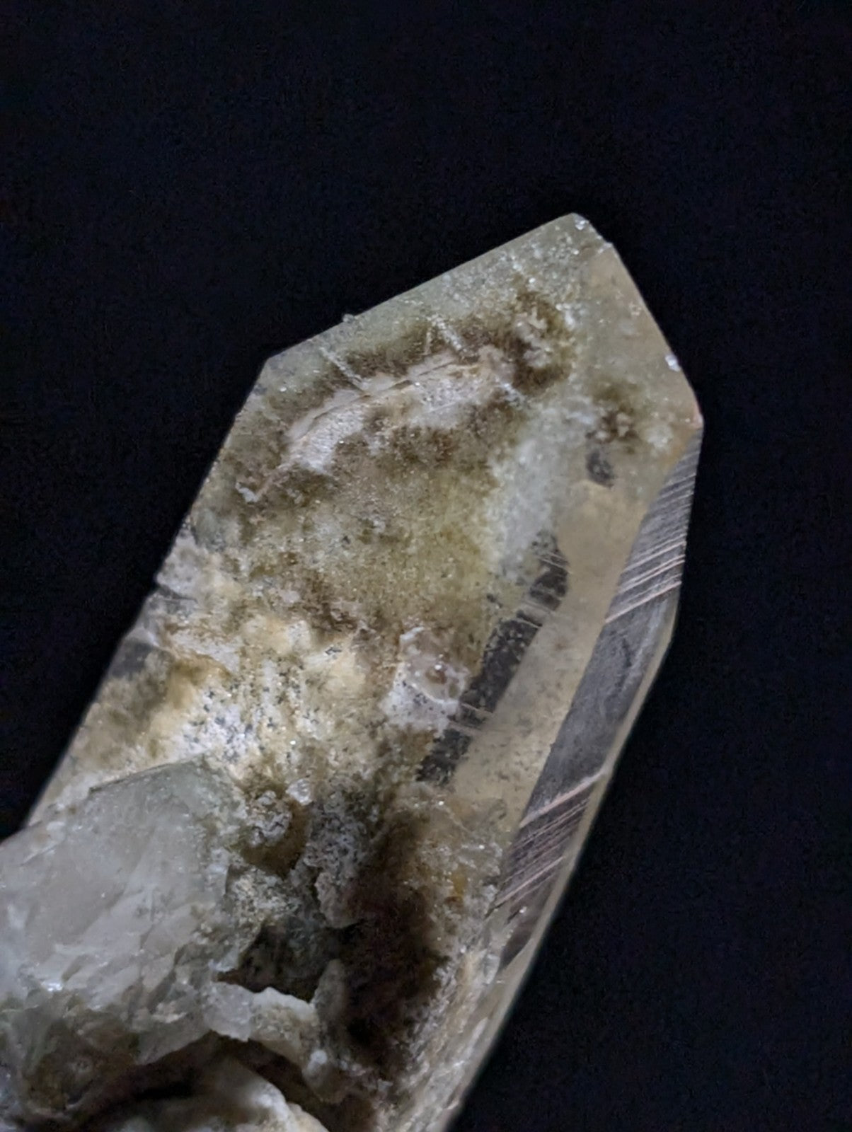 A translucent, pale quartz crystal with natural inclusions and a pointed tip.