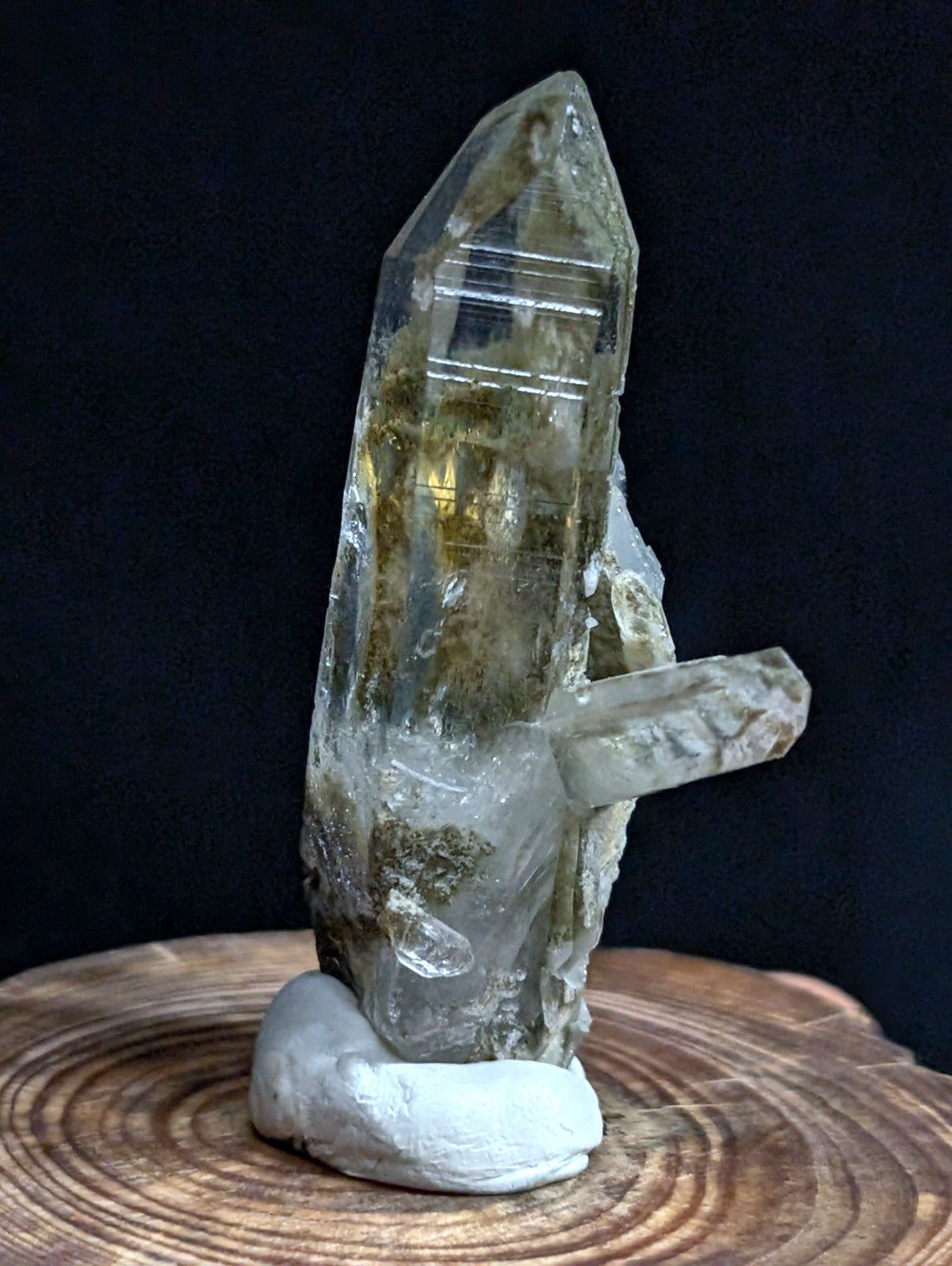 A translucent, clear quartz crystal with golden inclusions and a rough, natural base.