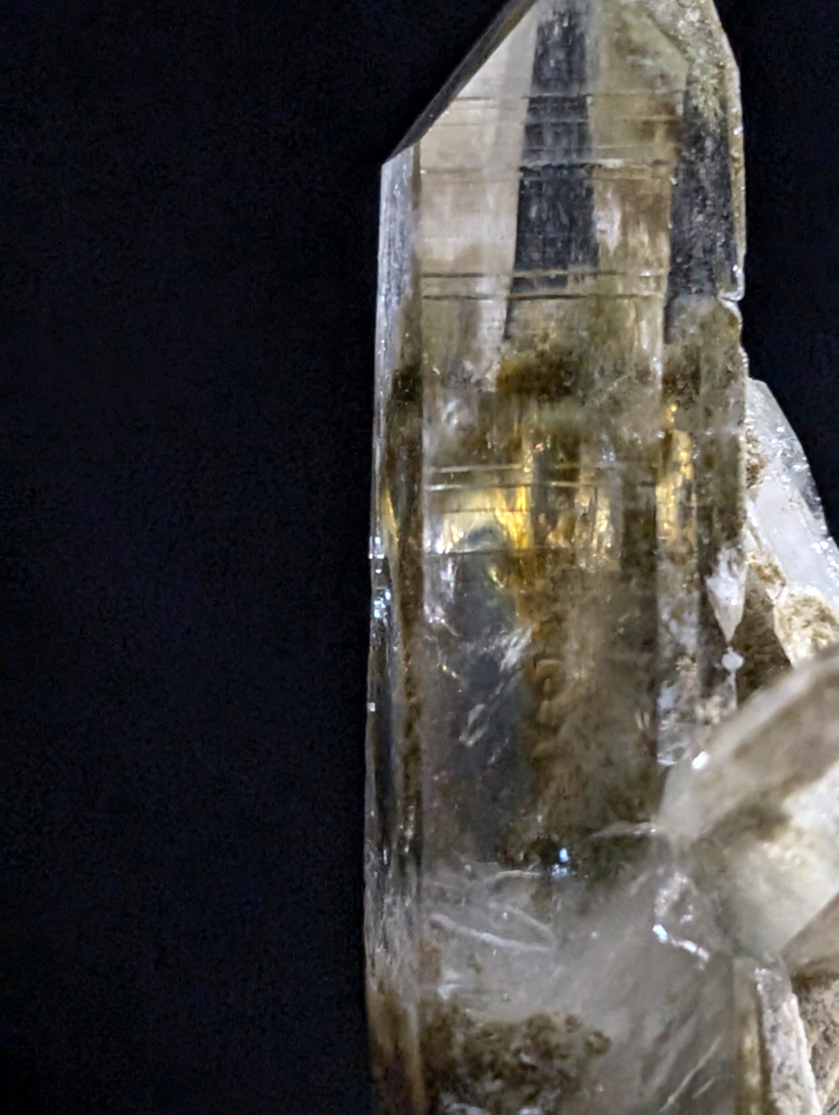 A translucent, amber-hued quartz crystal with visible internal inclusions and a faceted, pointed tip.