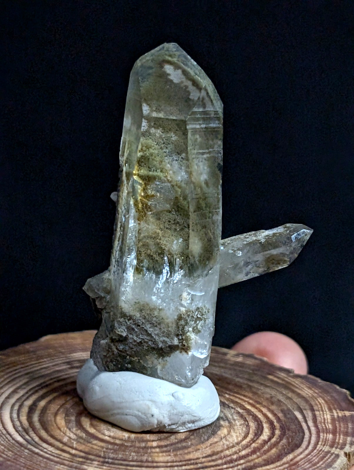 A translucent greenish quartz crystal cluster with natural inclusions, displayed on a white stone base.