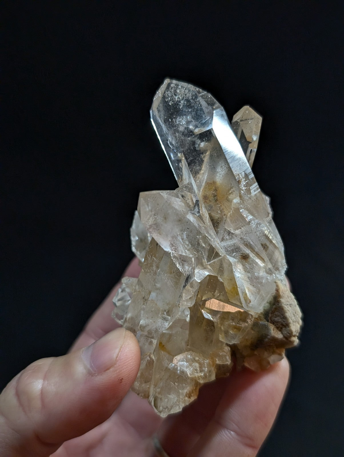A translucent, clear quartz crystal cluster with a prominent central point and smaller surrounding crystals.