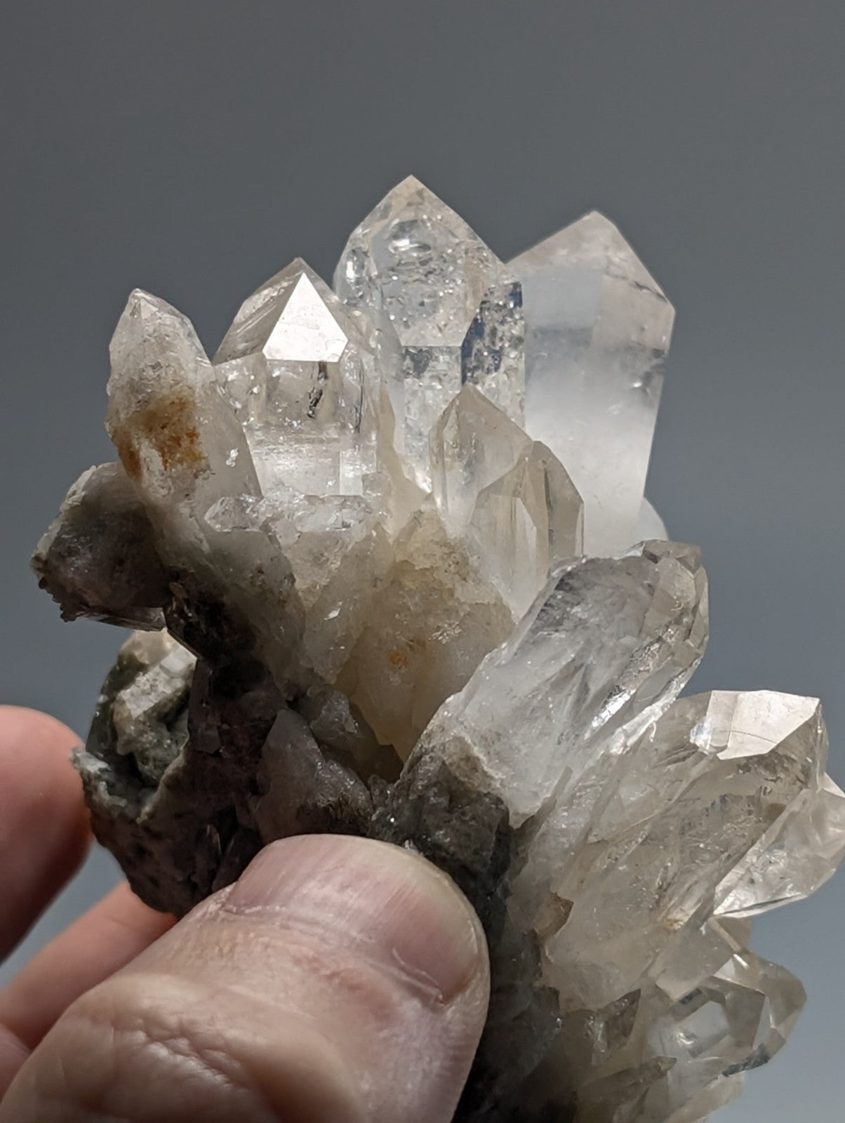 A cluster of clear, faceted quartz crystals with some exhibiting subtle golden hues and others displaying natural inclusions.