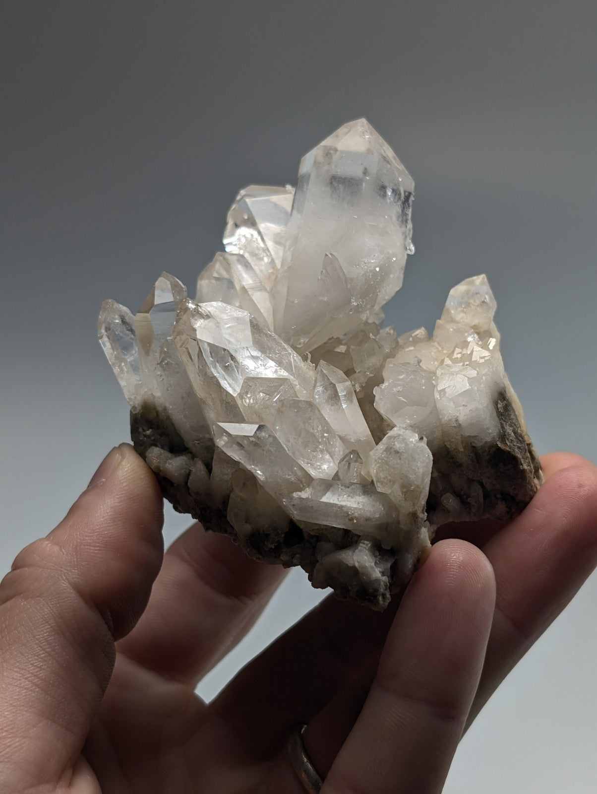 A clear quartz crystal cluster with sharp, faceted points and a translucent appearance.