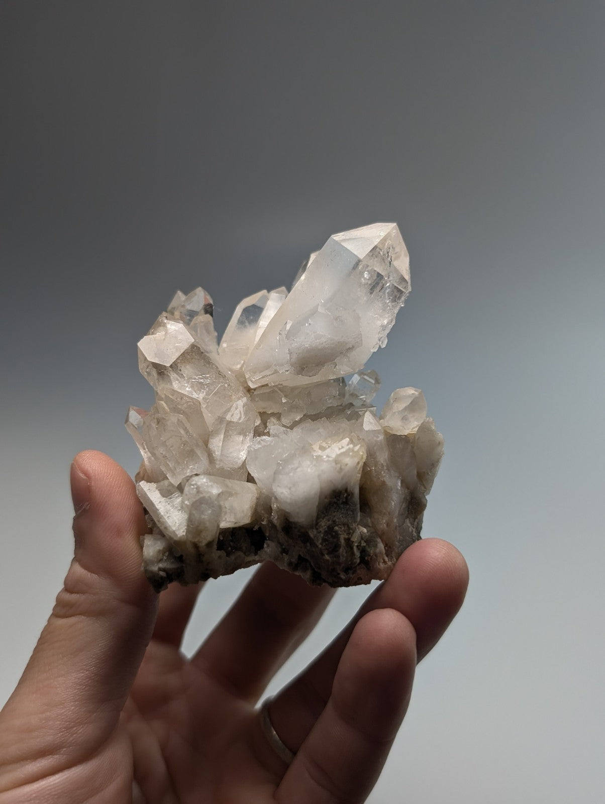 A clear quartz crystal cluster with sharp, faceted points and a translucent appearance.