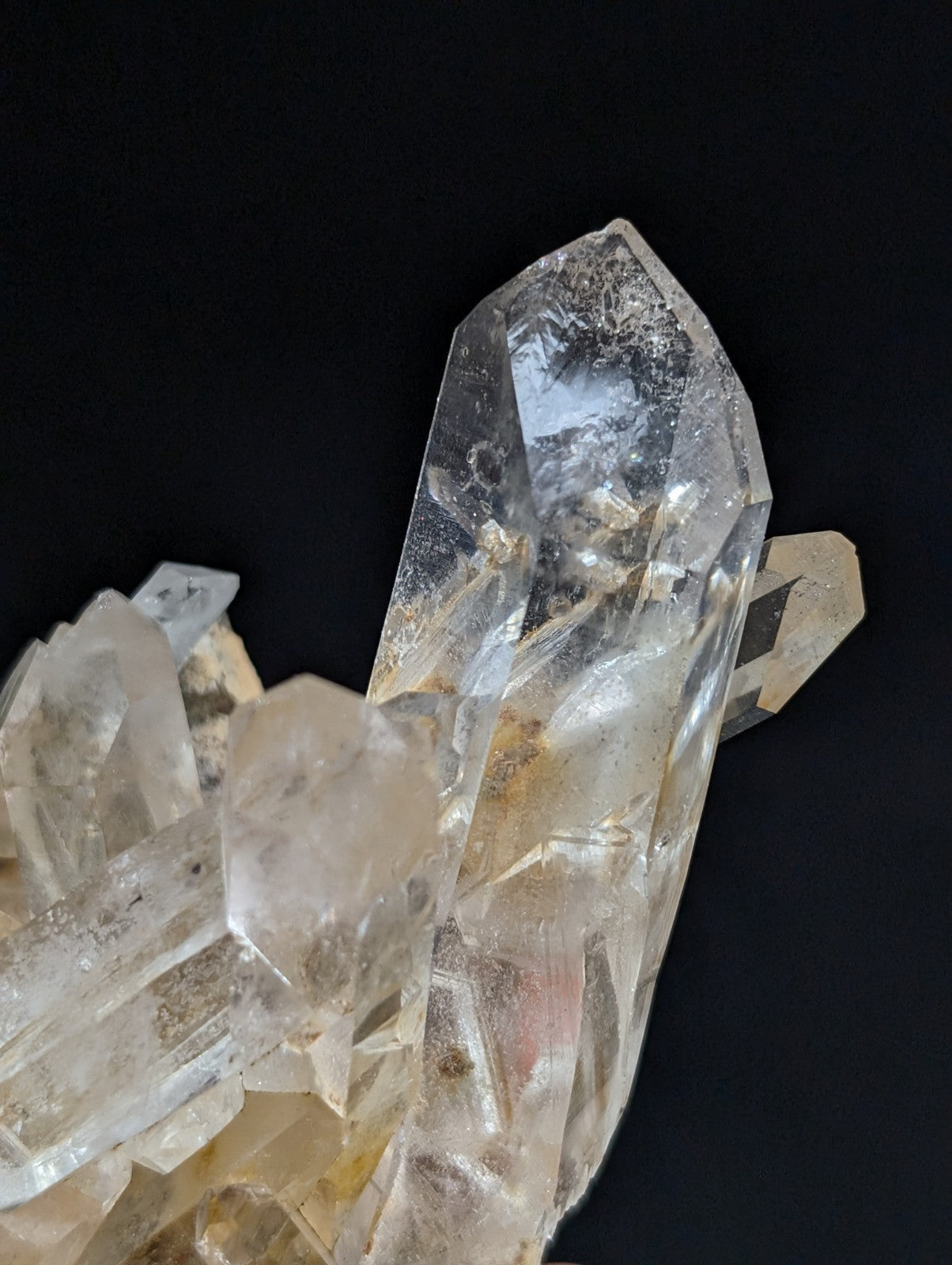 A cluster of translucent quartz crystals with sharp, faceted edges and subtle golden inclusions.