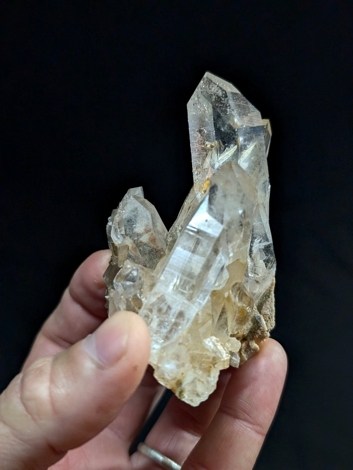 A translucent, clear quartz crystal cluster with sharp geometric facets and subtle golden inclusions.