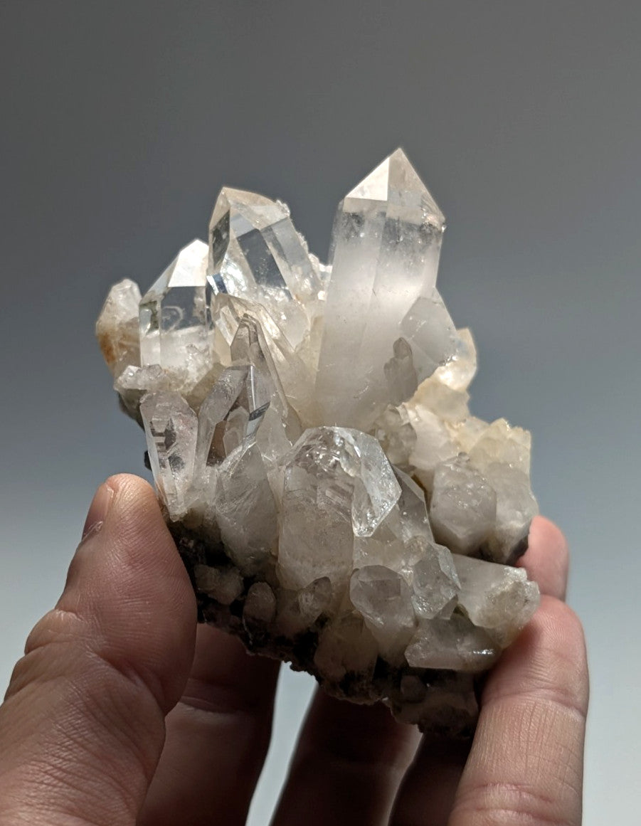 A clear quartz crystal cluster with sharp, faceted points and a translucent appearance.