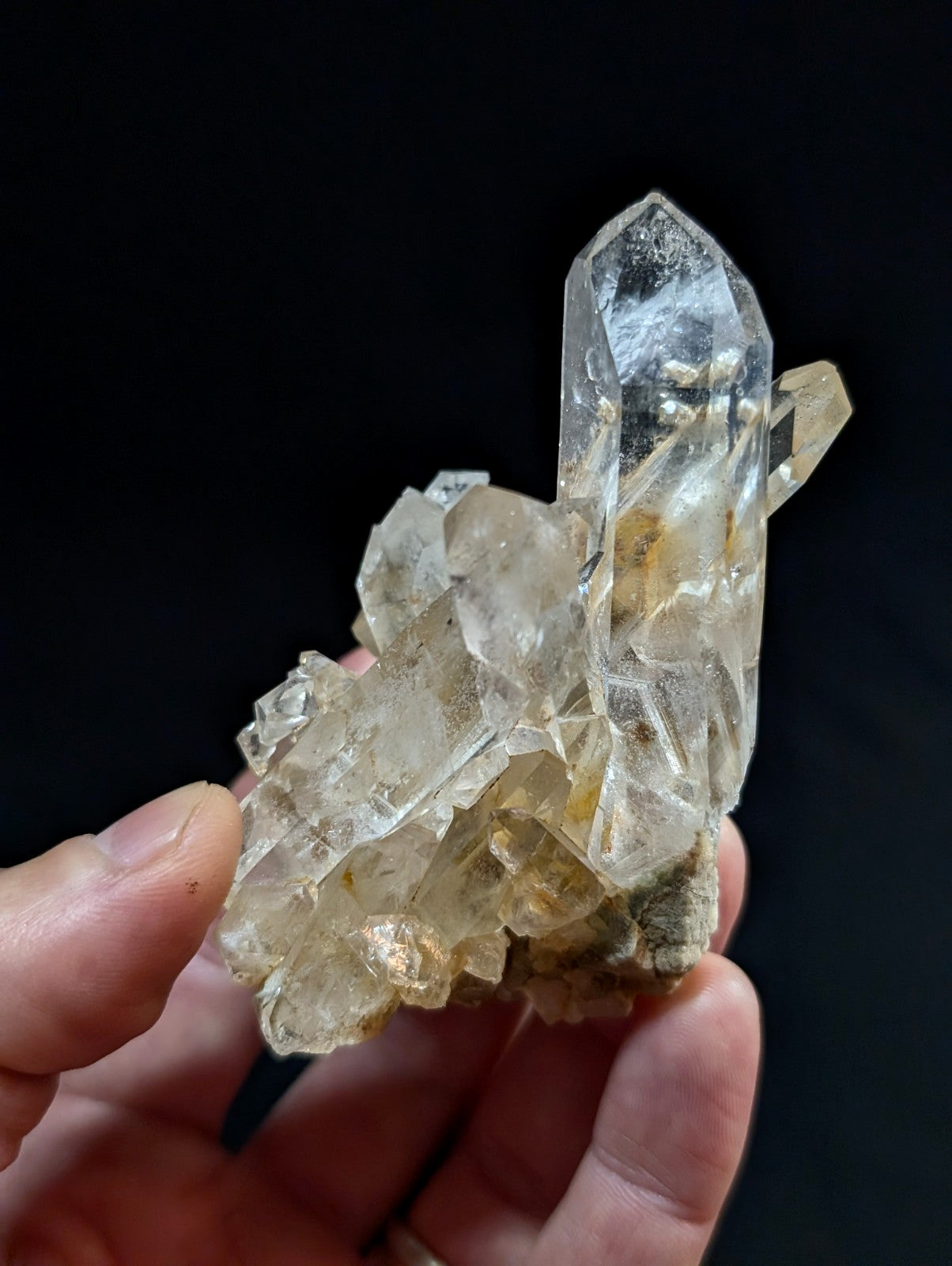 A translucent, clear quartz crystal cluster with a prominent tall point and smaller surrounding crystals.