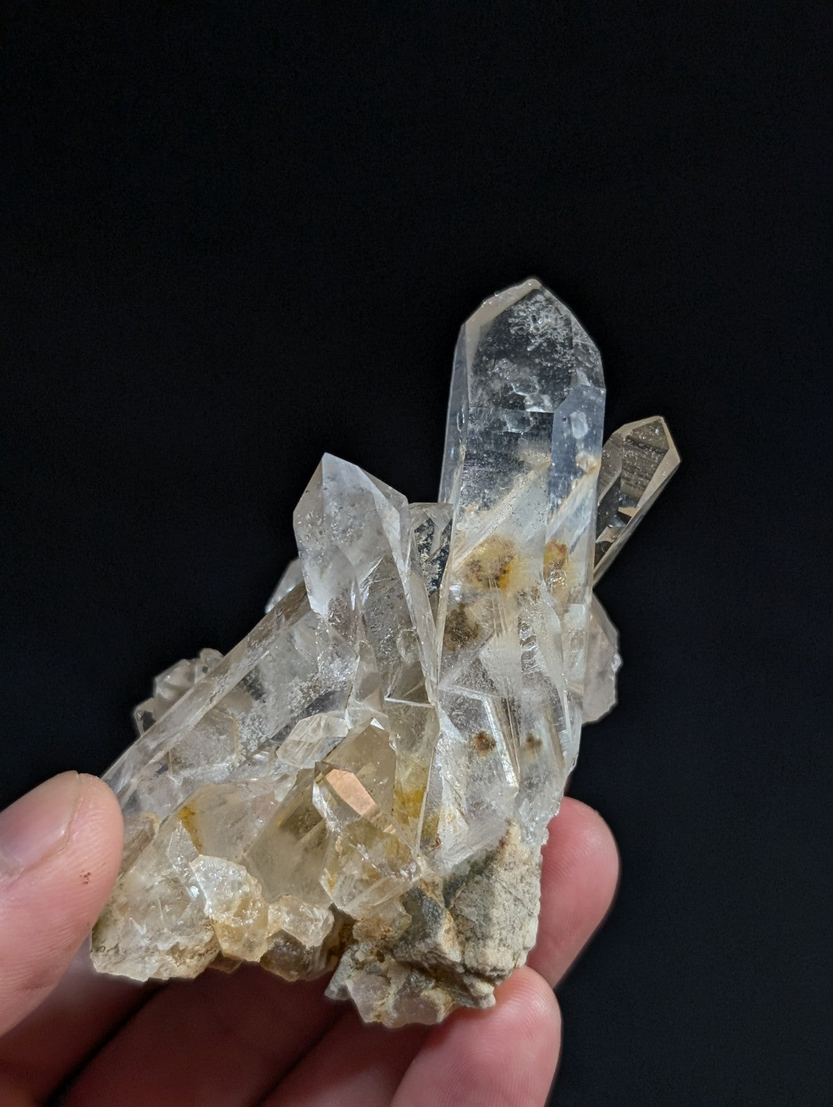 A clear quartz crystal cluster with sharp, faceted points and subtle golden inclusions.