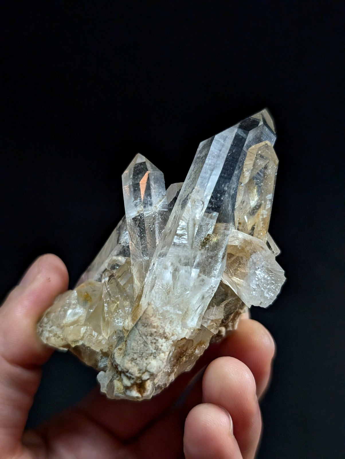 A cluster of clear, translucent quartz crystals with sharp facets and a few amber-tinted inclusions.