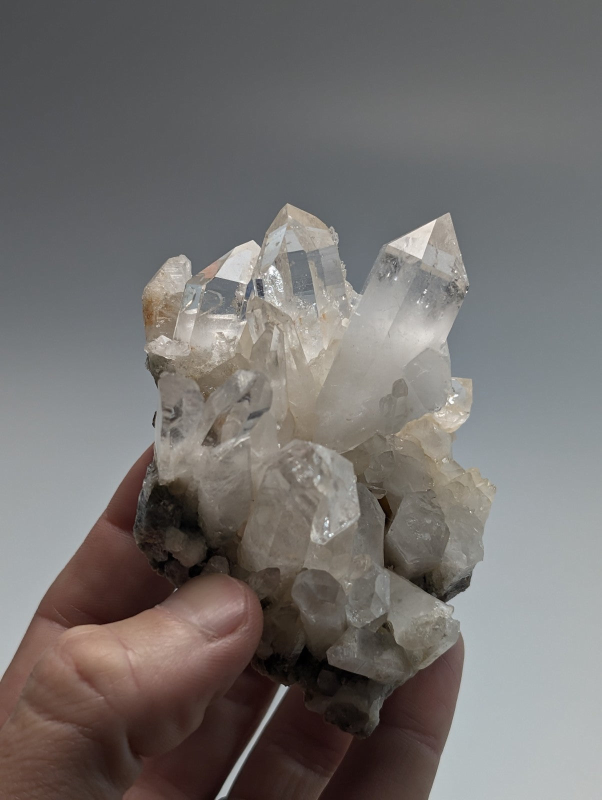 A clear quartz crystal cluster with sharp, faceted points and a translucent appearance.