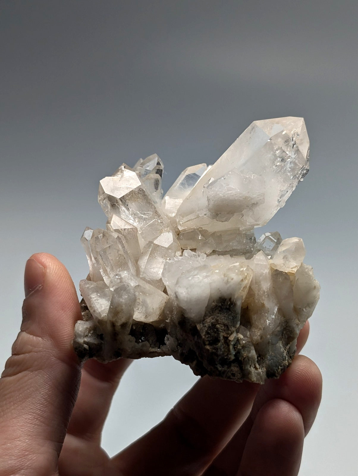 A translucent white quartz crystal cluster with sharp, faceted points and a rougher base.