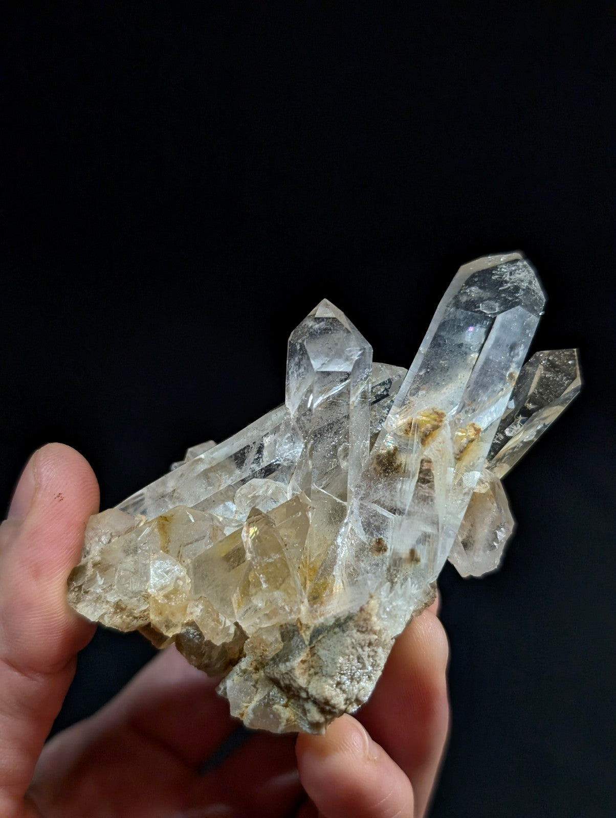 A clear quartz crystal cluster with translucent, faceted points and golden mineral inclusions.