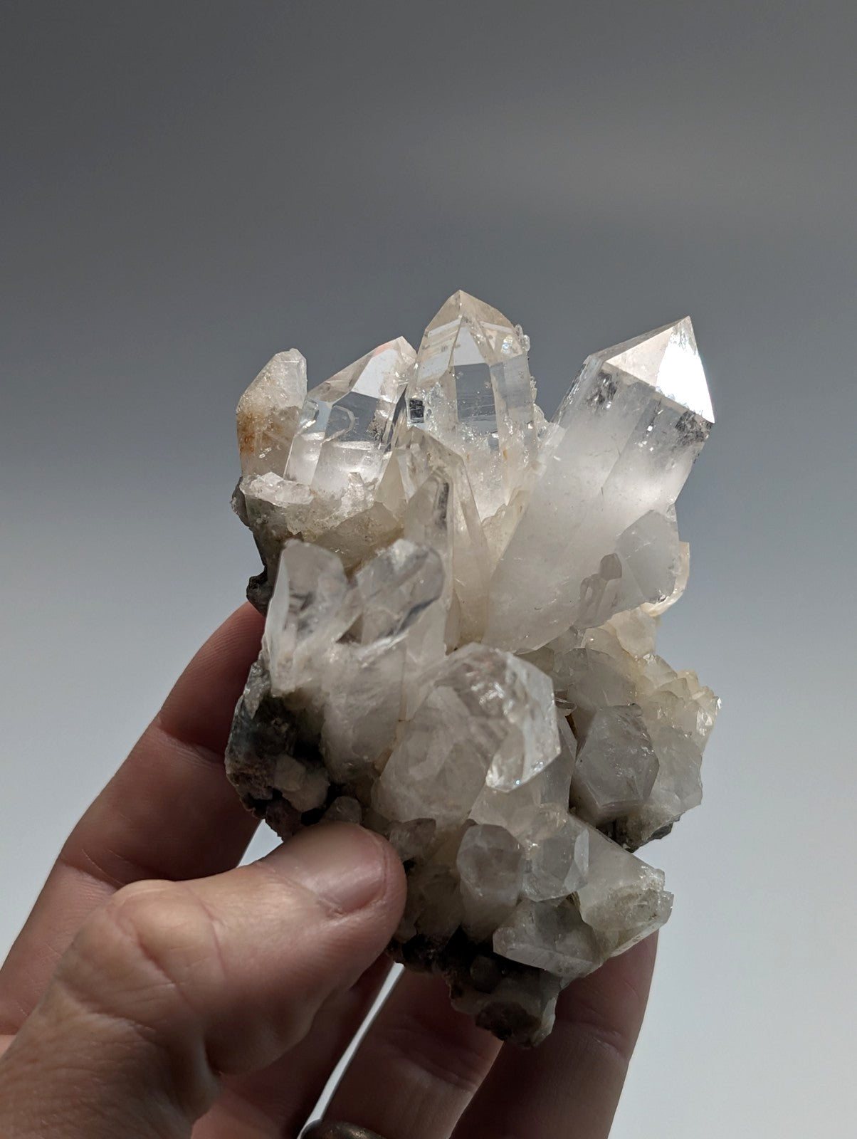 A cluster of clear, faceted quartz crystals with some exhibiting subtle white and gray veining.