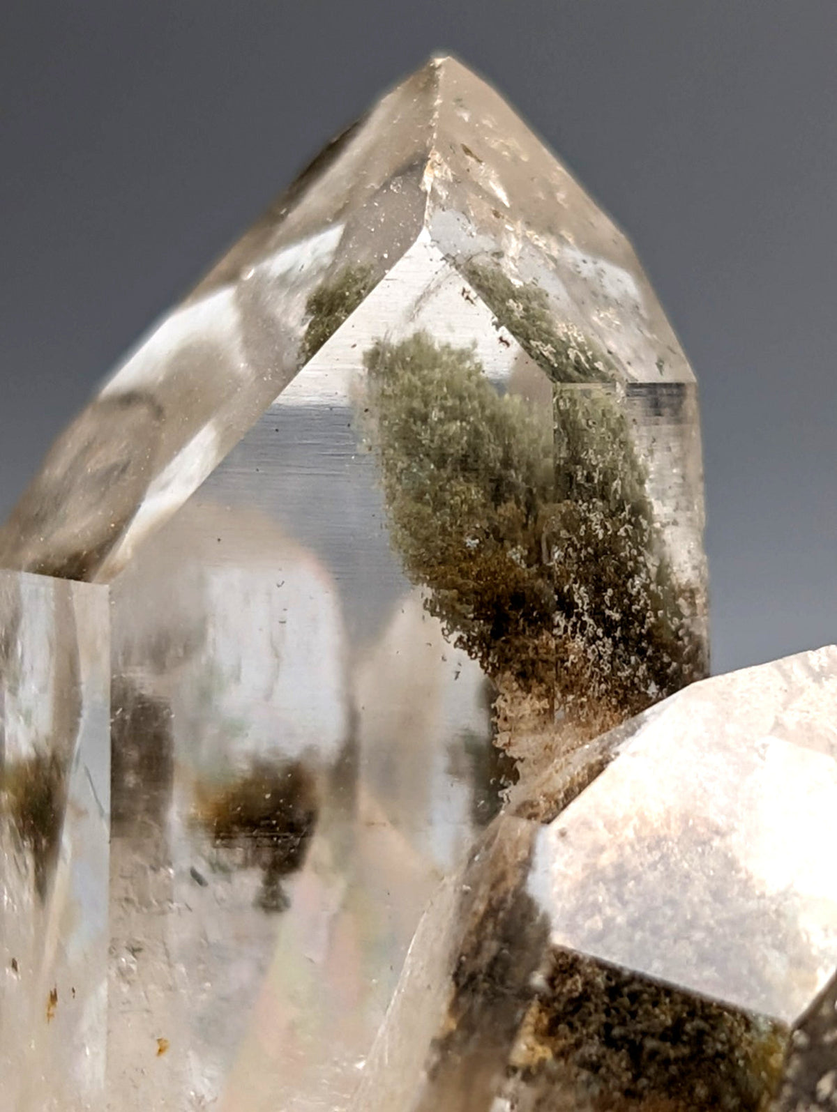 A clear quartz chlorite phantom crystal cluster with pointed facets and green moss inclusions from willis mine arkansas