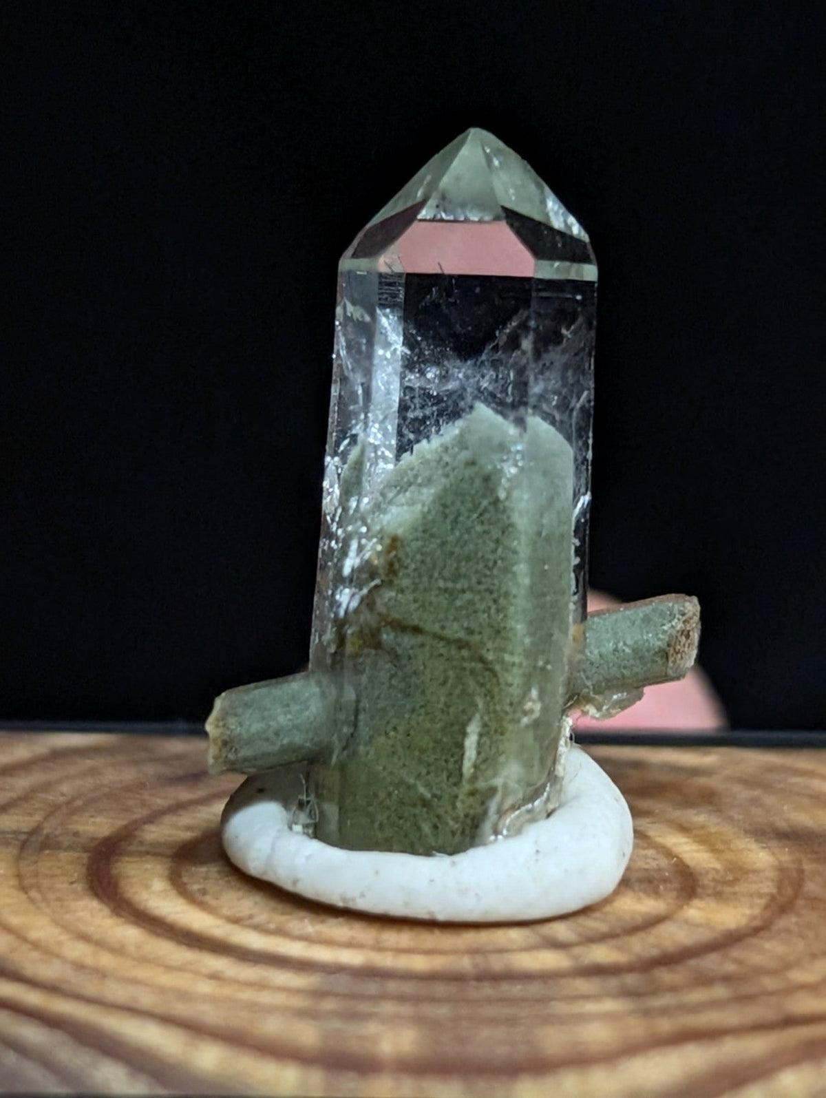 A clear quartz crystal with a greenish base and two short, rough-textured branches extending from its sides.