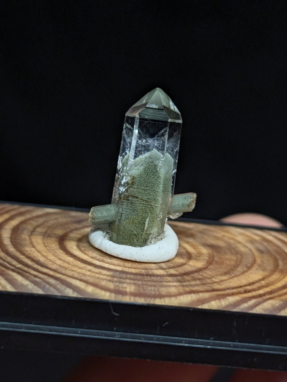 A clear quartz crystal with a greenish base and two short, stubby arms extending from its sides.