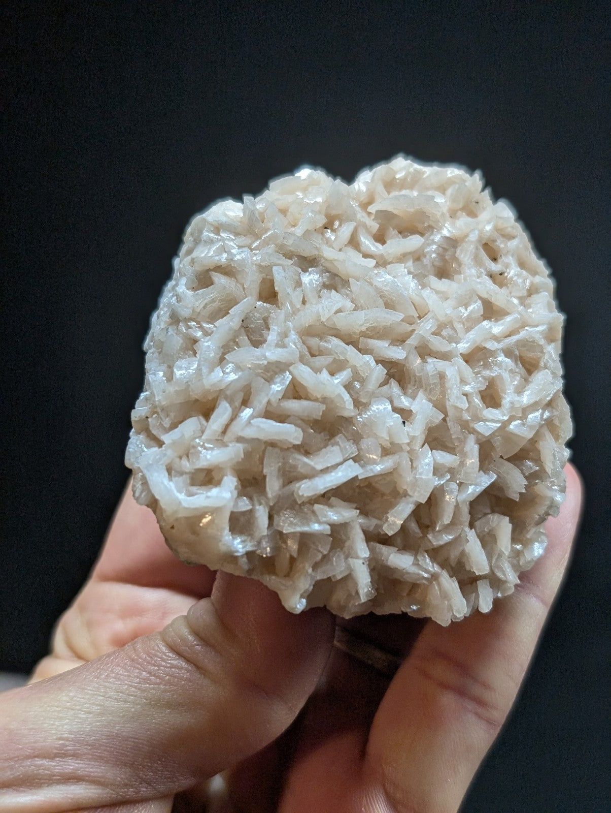 A translucent, pale white crystal cluster with a rough, textured surface composed of numerous interlocking needle-like formations.