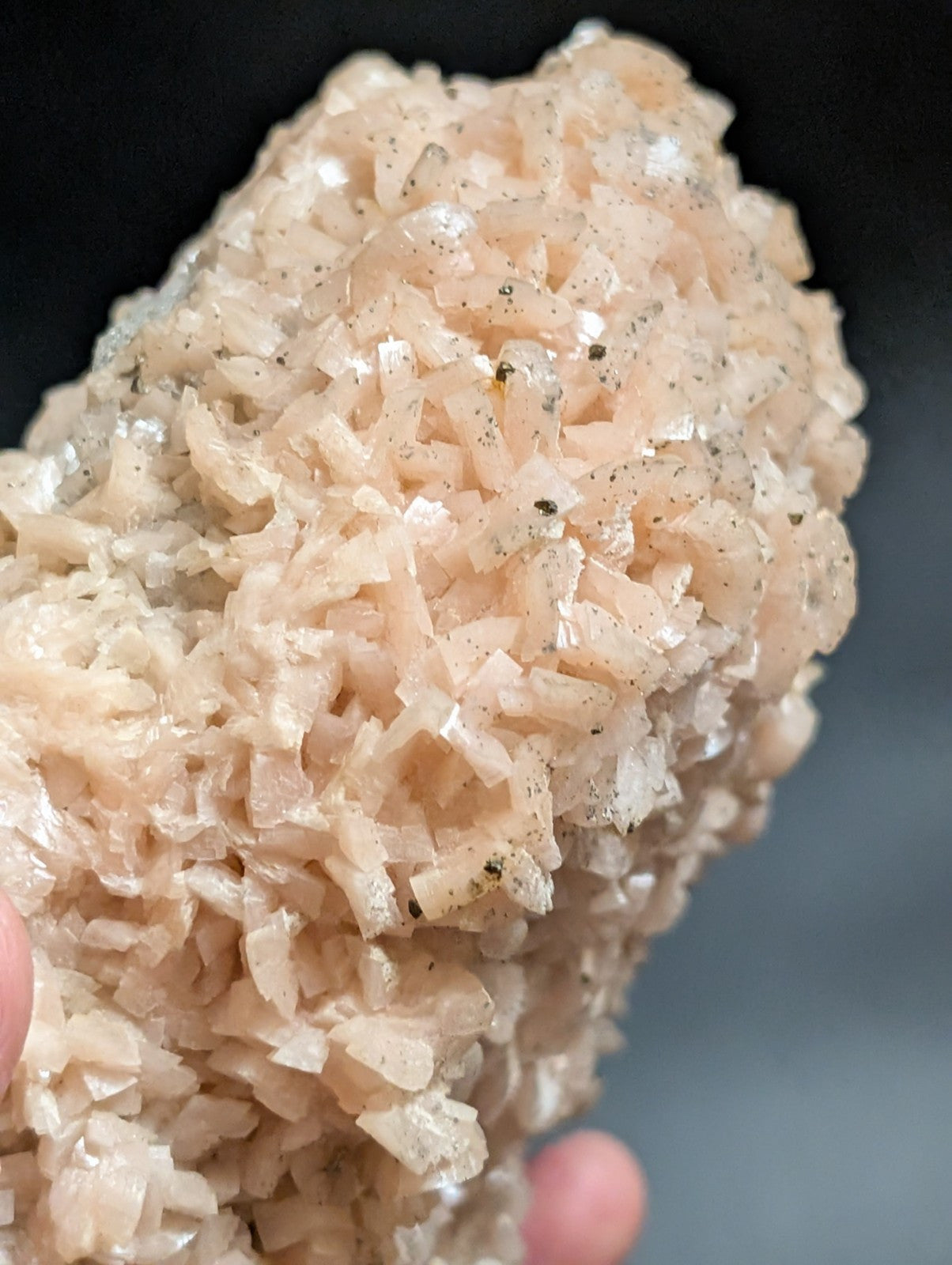 A pale pink, translucent mineral specimen with a crystalline texture and scattered dark inclusions.