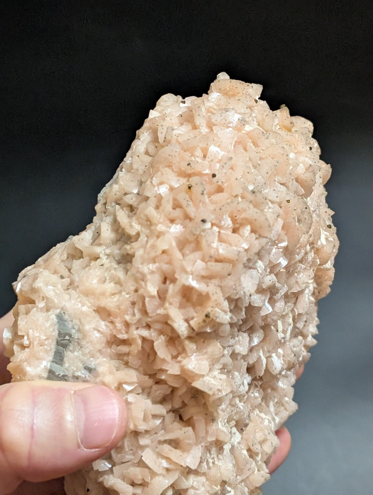 A pale pink, translucent mineral specimen with a crystalline texture and scattered dark specks.