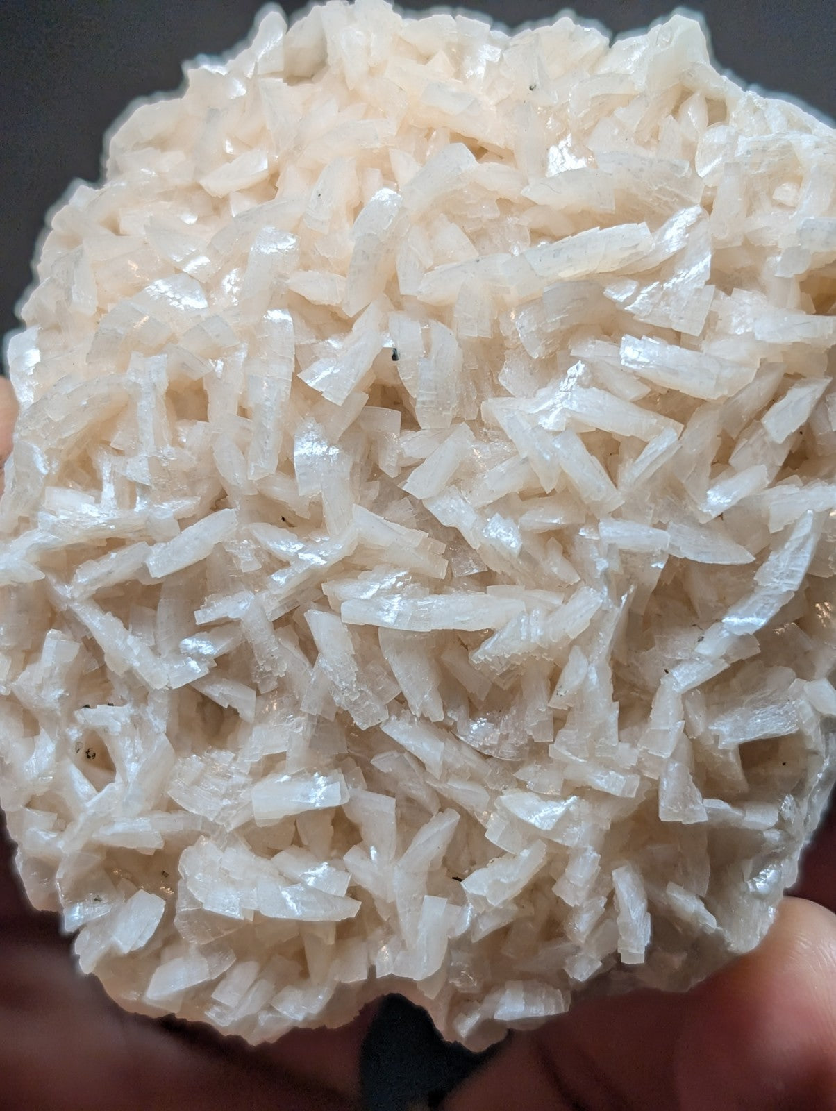 A cluster of translucent, off-white crystalline formations with sharp, jagged edges and a rough, textured surface.