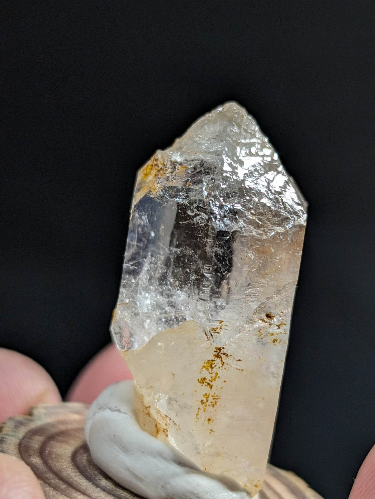 A translucent, clear quartz crystal with golden inclusions and a pointed tip.