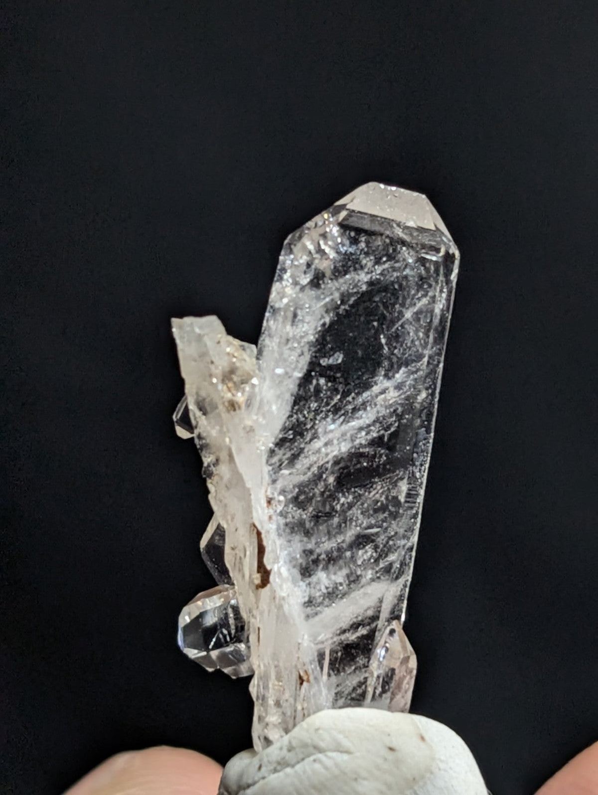 A clear, translucent quartz crystal cluster with a prominent central column and smaller crystals branching off to the side.