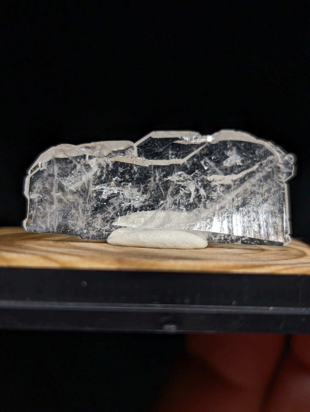 A translucent, naturally fractured piece of selenite crystal with a smooth, glassy surface and subtle internal striations.