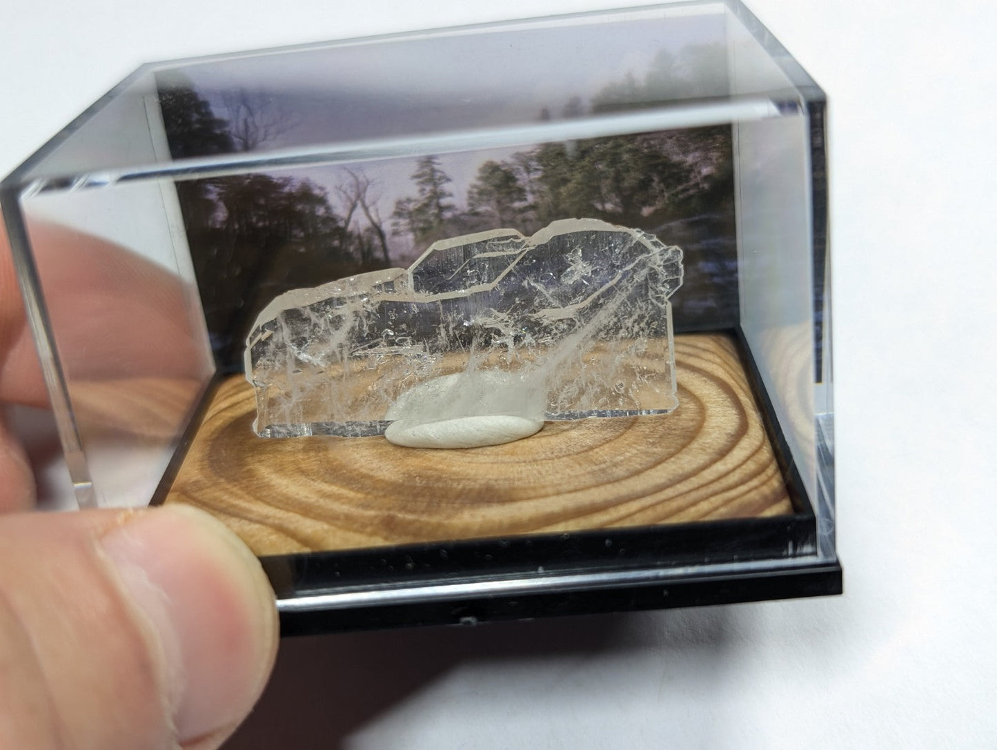 A transparent, intricately carved crystal car model displayed in a clear acrylic case.