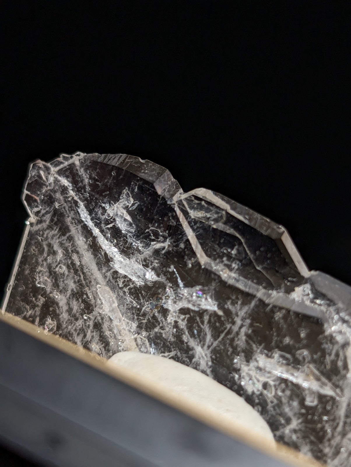 A fractured, translucent crystal with a dark base and intricate white veining.