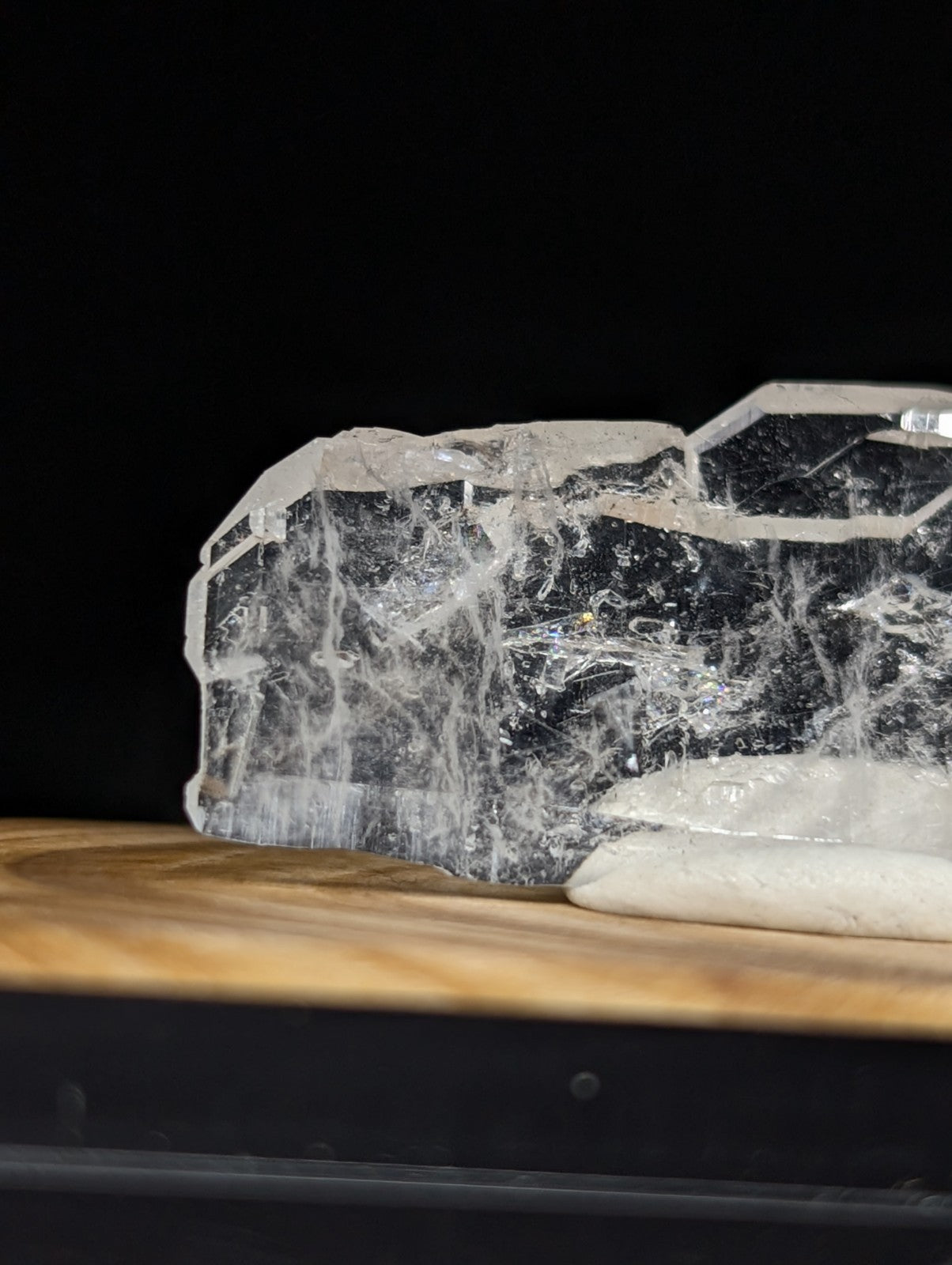 A translucent, clear quartz crystal with intricate internal veining and a rough, natural edge.