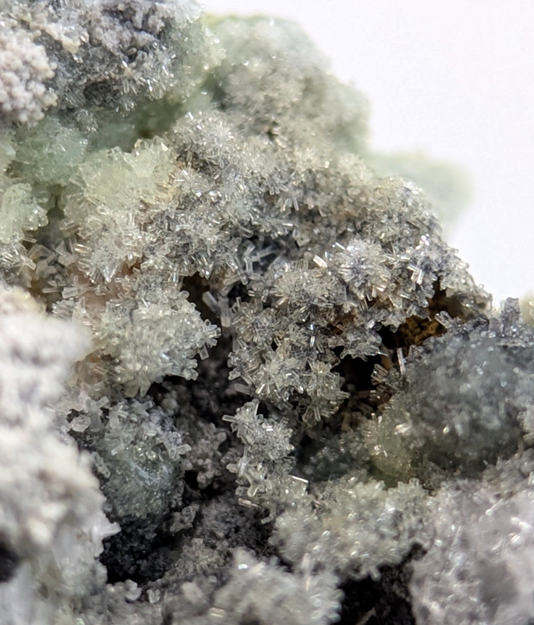 A cluster of translucent, crystalline minerals with a mix of pale green and gray hues.