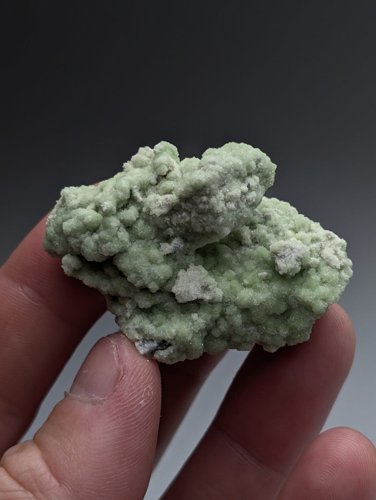 A pale green fluorwavellite mineral with rough crystalline texture intermixed with sio2 from mauldin mountain arkansas held in fingers