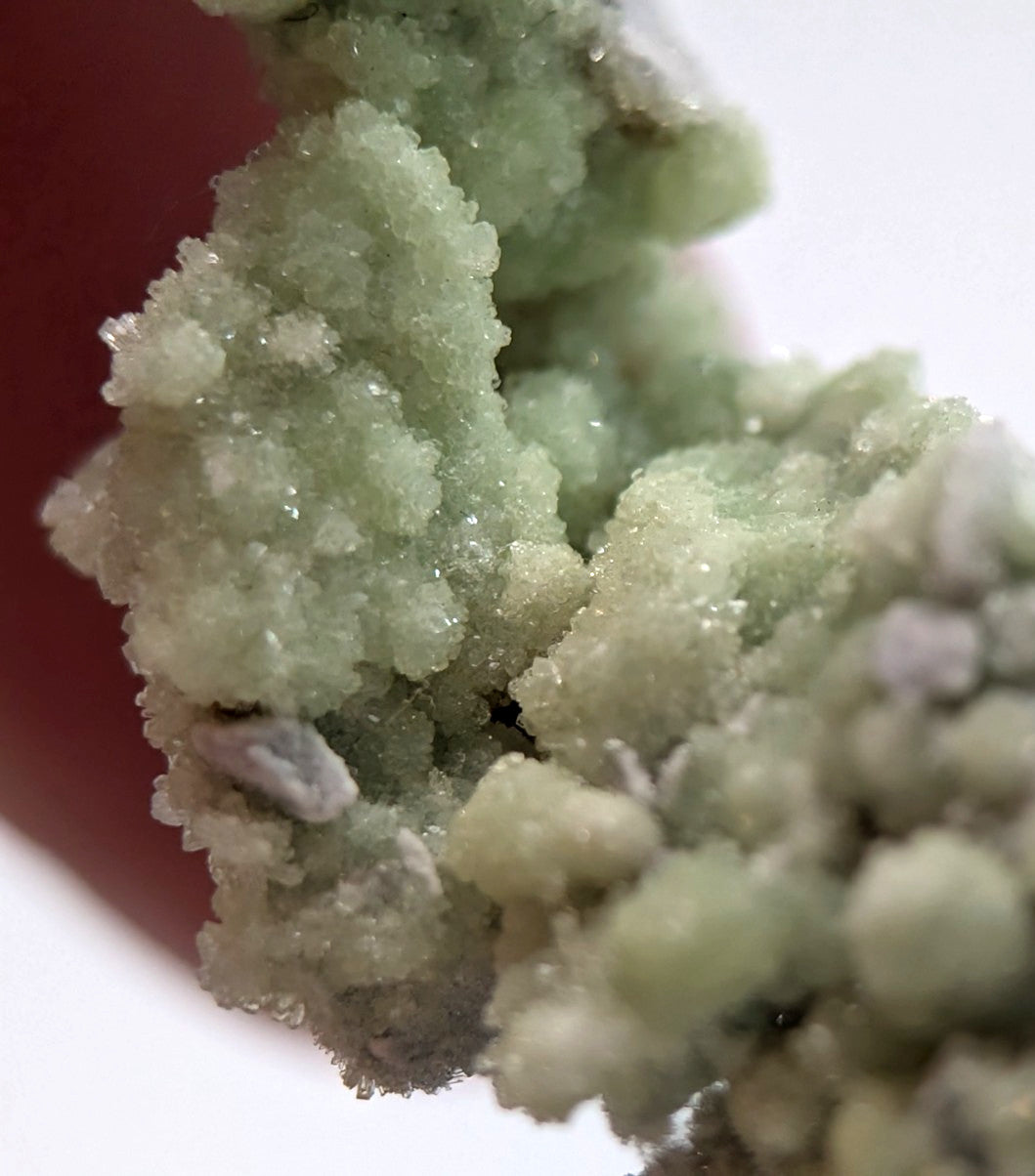 A cluster of pale green, crystalline minerals with a rough, textured surface.