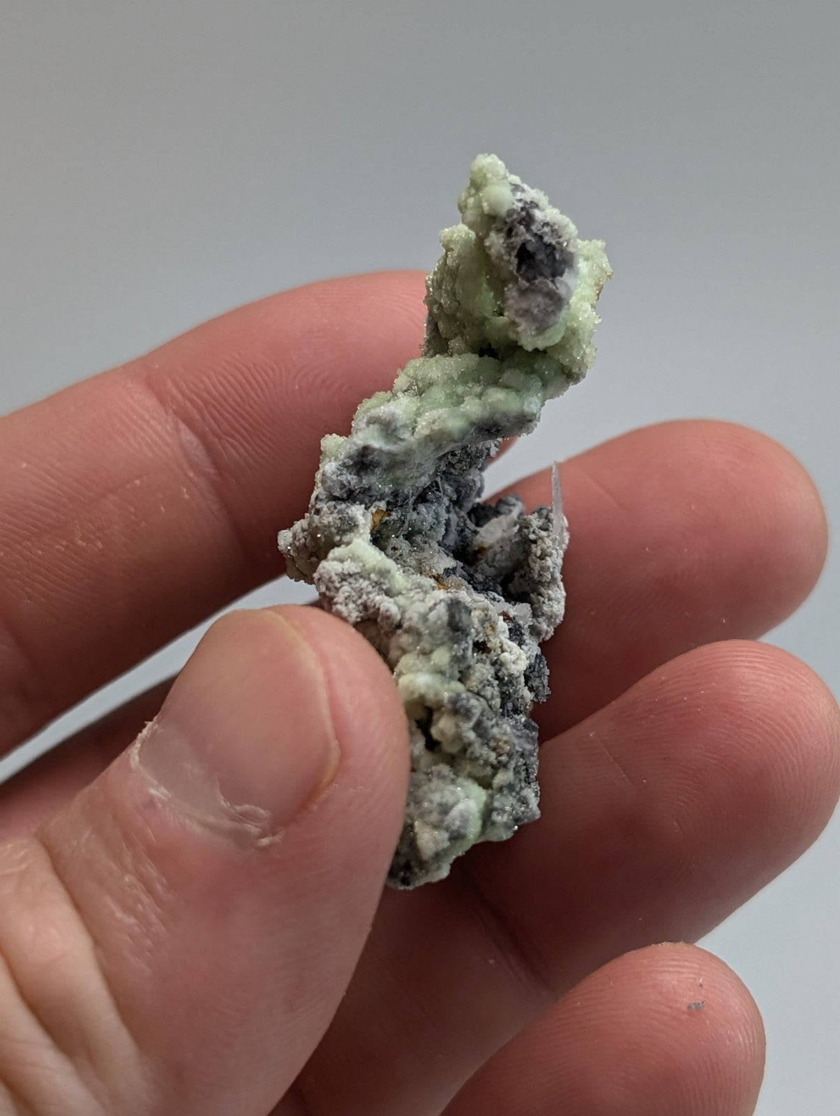 A textured, irregularly shaped mineral specimen with a mottled green and gray surface.