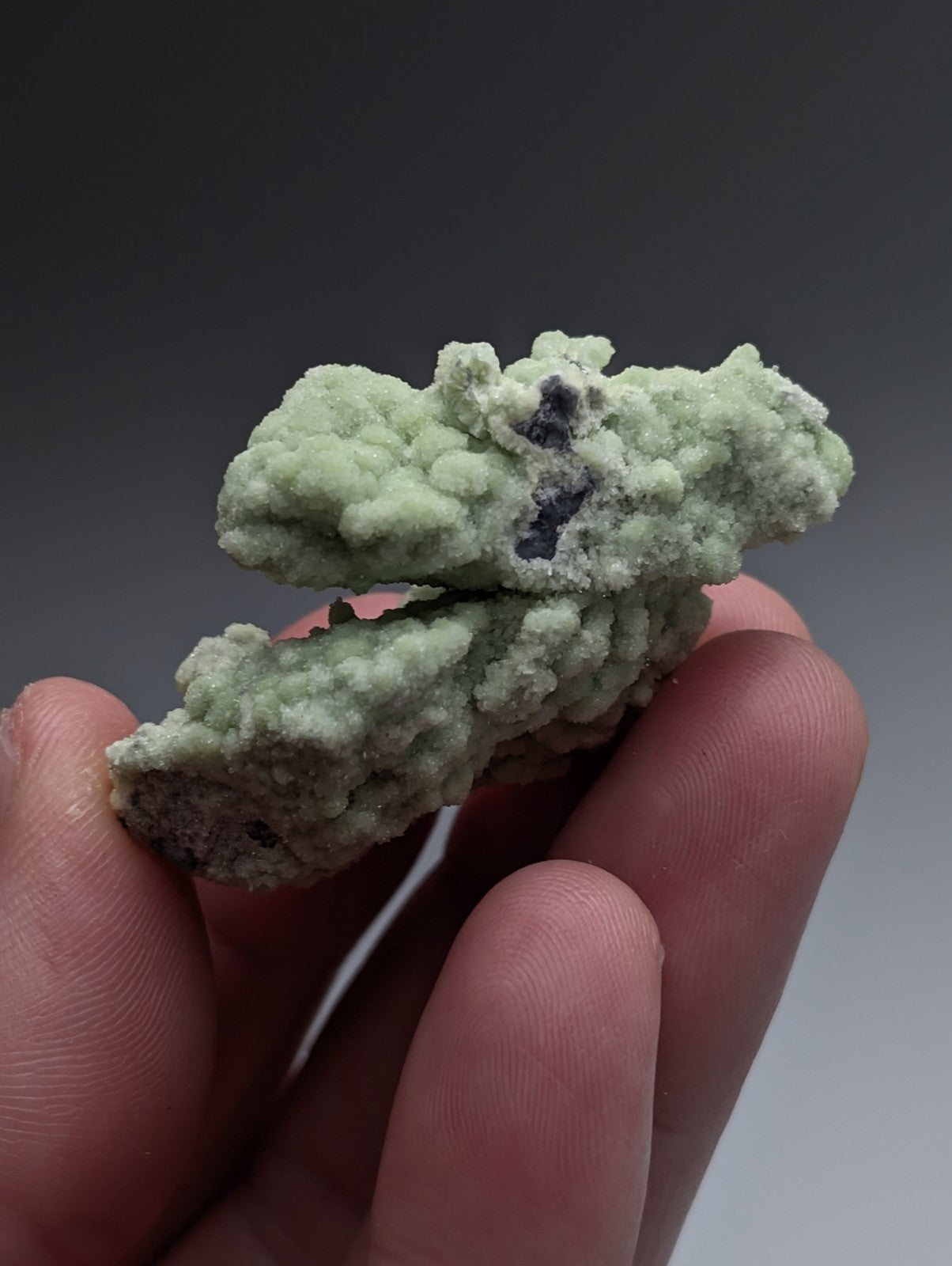 A pale green A+ fluorwavellite mineral with rough crystalline surface and dark inclusions from Mauldin Mountain Arkansas