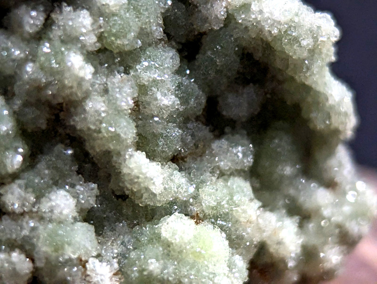 A cluster of translucent, pale green crystals with a sugary, crystalline texture.