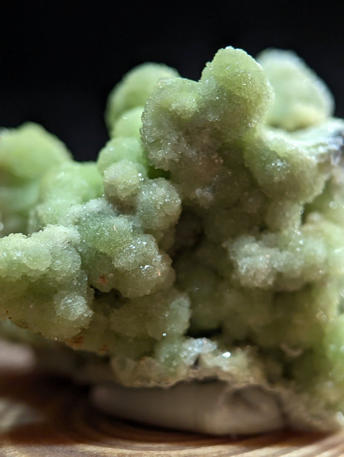A cluster of translucent, pale green crystalline formations with a sugary texture and subtle iridescence.