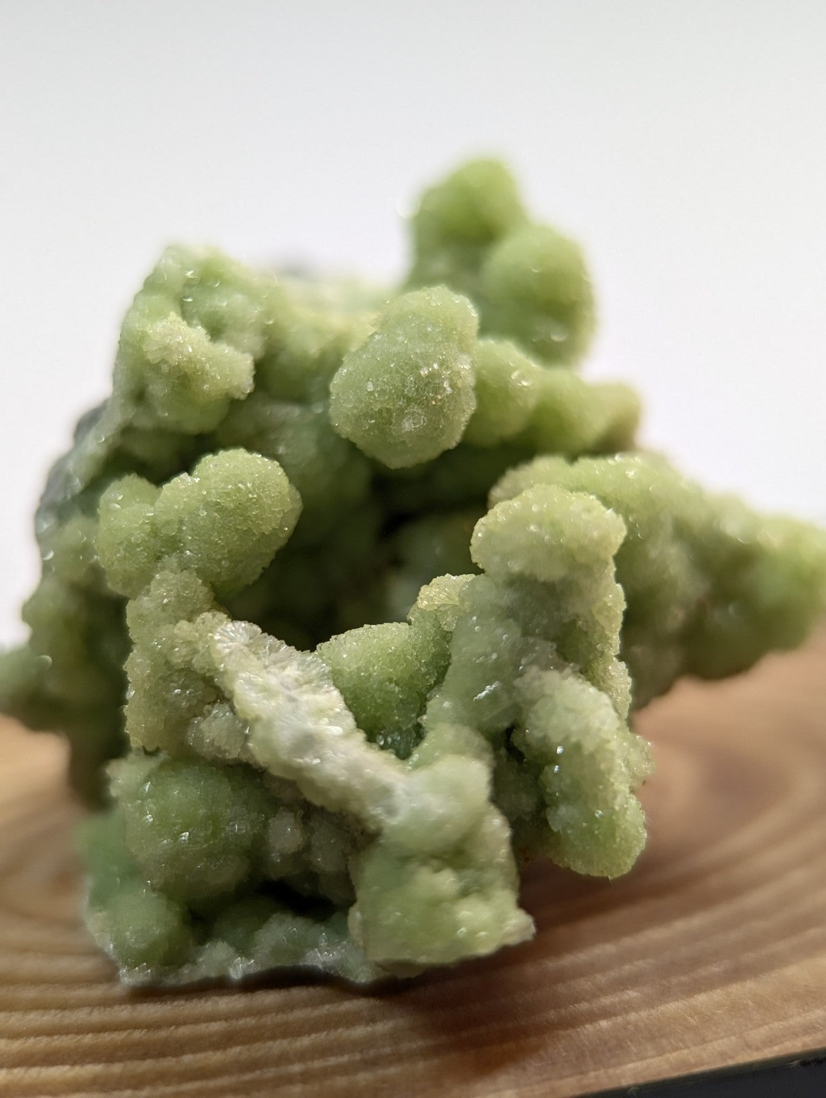 A cluster of pale green, crystalline mineral formations with a rough, textured surface.