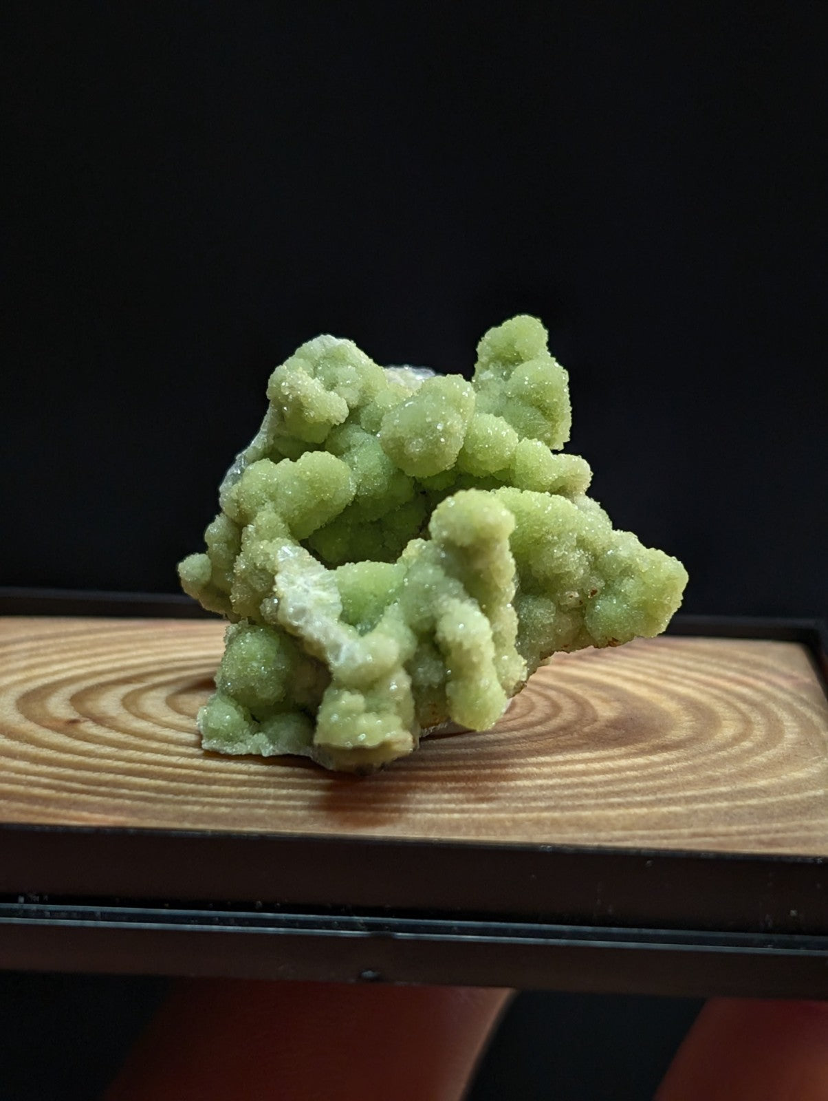 A vibrant green, crystalline mineral specimen with a textured, branching structure.