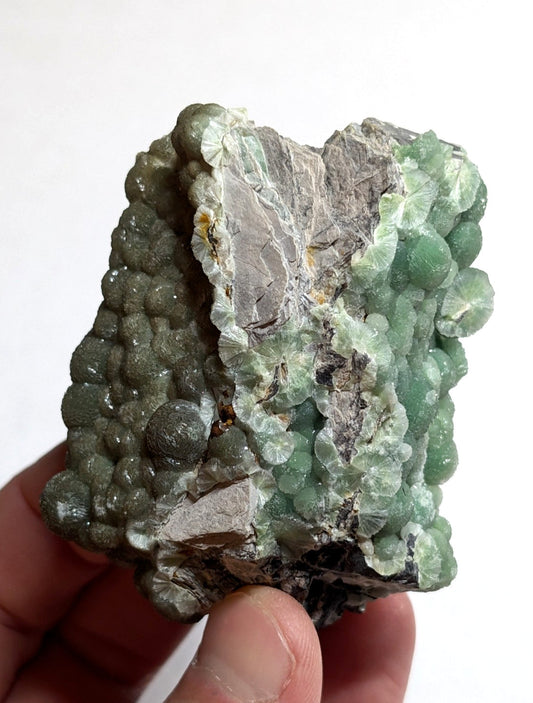 A green, translucent mineral specimen with a textured surface featuring rounded nodules and crystalline formations.