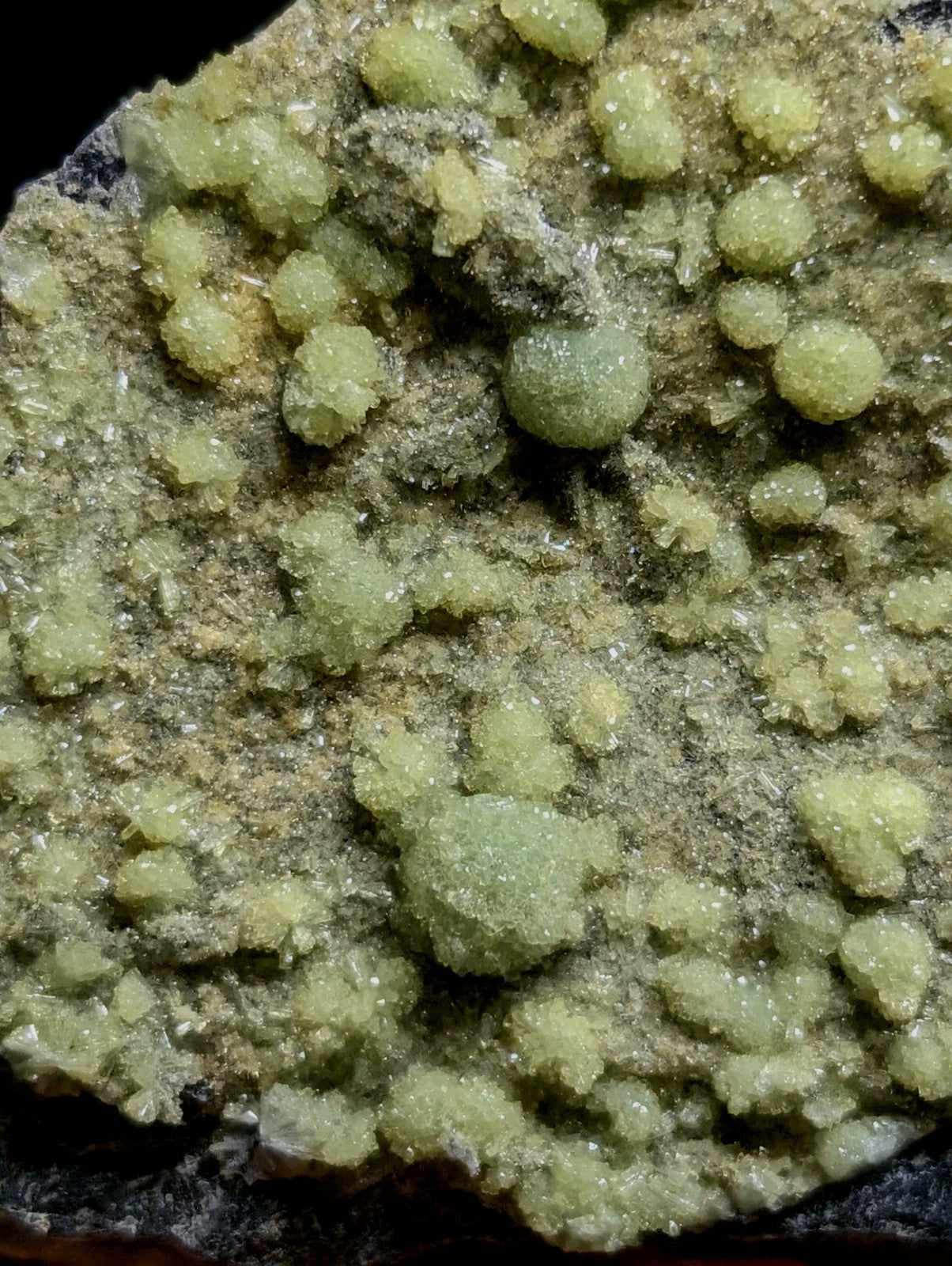 A cluster of translucent, pale green crystalline formations with a rough, textured surface.