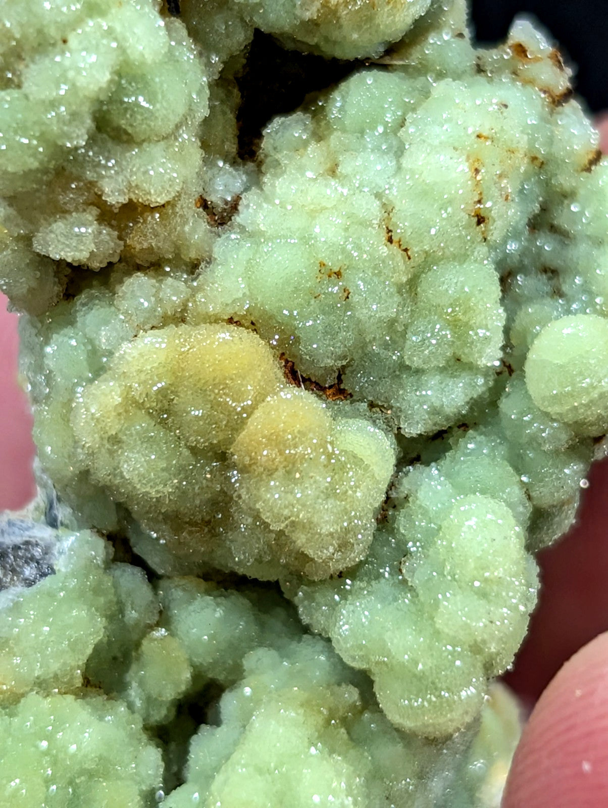 A cluster of pale green, crystalline minerals with a sugary texture and subtle yellowish-brown streaks.